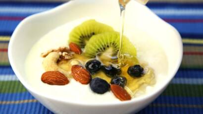 Sałatka owocowa z jogurtem w białej misce. Widać różne owoce.